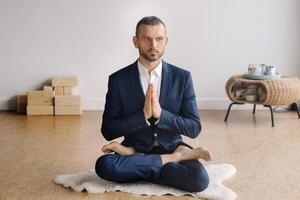 un hombre en un estricto traje lo hace yoga mientras sentado en un aptitud habitación foto