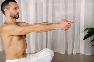 a man with a bare torso does yoga in a fitness room. the concept of a healthy lifestyle photo