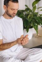 un hombre en blanco ropa de deporte es haciendo yoga con un aptitud habitación. el concepto de un sano estilo de vida foto