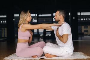 a woman and a man are engaged in pair gymnastics yoga in the gym photo