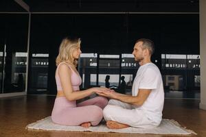 un mujer y un hombre son comprometido en par meditación participación manos en el gimnasio foto