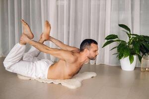 un hombre con un desnudo torso lo hace yoga en un aptitud habitación. el concepto de un sano estilo de vida foto