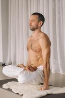 a man with a bare torso does yoga in a fitness room. the concept of a healthy lifestyle photo