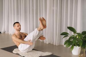 un hombre con un desnudo torso lo hace yoga en un aptitud habitación. el concepto de un sano estilo de vida foto