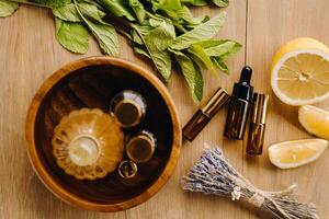 Essential oil in bottles with the aroma of lemon, mint and lavender, lying on a wooden surface photo