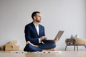 A man in a formal suit works sitting in a fitness room on a laptop photo