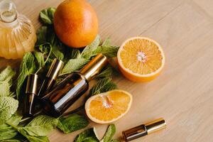 Essential oil in bottles with the aroma of orange and mint lying on a wooden surface photo