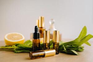 Essential oil in bottles with lemon and mint fragrance lying on a wooden surface photo