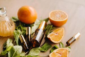 Essential oil in bottles with the aroma of orange and mint lying on a wooden surface photo