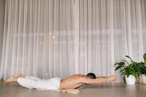 a man with a bare torso does yoga in a fitness room. the concept of a healthy lifestyle photo