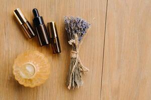 Essential oil in one bottle and dried lavender standing on the surface photo