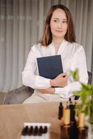 portrait of a smiling girl-woman sitting in an armchair. An aromatherapist in a white blouse is sitting in the office photo