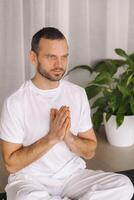 a man in white sportswear is doing yoga with a fitness room. the concept of a healthy lifestyle photo