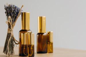 Essential oil in one bottle and dried lavender standing on the surface photo