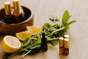 Essential oil in bottles with lemon and mint fragrance lying on a wooden surface photo