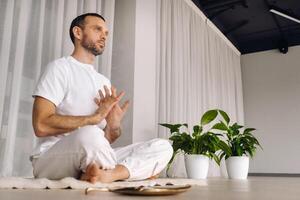 de cerca de un hombre en blanco ropa de deporte haciendo yoga en un aptitud habitación con un balgovón. el concepto de un sano estilo de vida foto