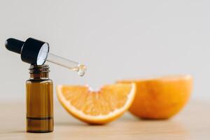 Essential oil in one bottle and orange slices lying on the surface photo