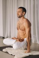 un hombre con un desnudo torso lo hace yoga en un aptitud habitación. el concepto de un sano estilo de vida foto