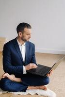 A man in a formal suit works sitting in a fitness room on a laptop photo