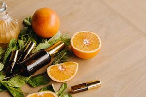 Essential oil in bottles with the aroma of orange and mint lying on a wooden surface photo