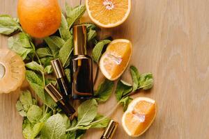 Essential oil in bottles with the aroma of orange and mint lying on a wooden surface photo