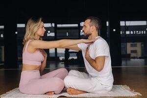 a woman and a man are engaged in pair gymnastics yoga in the gym photo