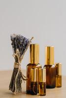 Essential oil in one bottle and dried lavender standing on the surface photo