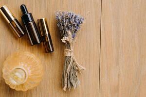 Essential oil in one bottle and dried lavender standing on the surface photo