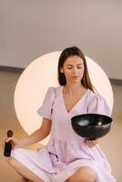 Portrait of a female yoga teacher playing a Tibetan bowl or singing a bell in the gym during a yoga retreat photo