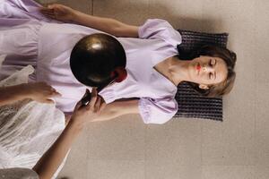 The copper singing bowl of the Nepalese Buddha in the spa. A young beautiful woman is doing a massage with singing bowls in a spa salon against the backdrop of a waterfall photo