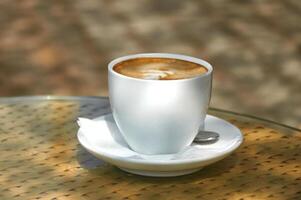 capuchino en un blanco taza en el mesa en un soleado día foto