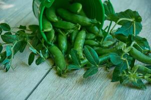 verde chícharos en un pequeño verde Cubeta en un de madera antecedentes foto