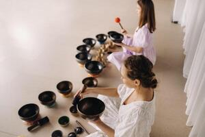 Two female yoga teachers play on Tibetan bowls in the gym during a yoga retreat photo