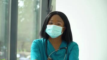 joven africano mujer médico en azul protector máscara mirando a el cámara video