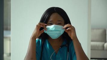africano fêmea médico coloca em médico mascarar dentro clínica. saúde proteção coronavírus conceito video
