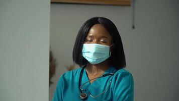 jovem africano mulher médico dentro azul protetora mascarar olhando às a Câmera video