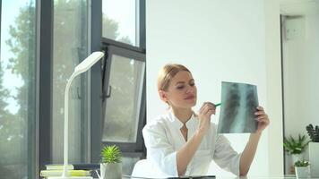 Female doctor studying X-ray scan and writes the result in a notebook. Healthcare, medicine concept video