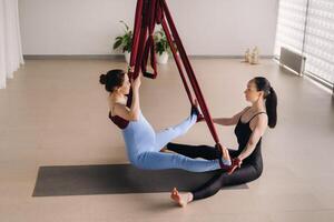 embarazada muchacha. un mujer con un entrenador lo hace yoga en un hamaca en el gimnasia. el concepto de un sano estilo de vida, maternidad foto