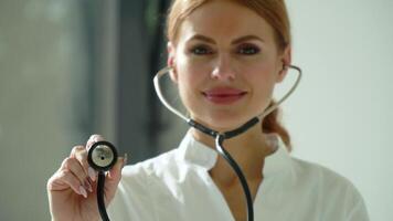 Close-up of woman doctor in white coat in clinic at workplace holds stethoscope in his hand and listens to breathing of potential patient. Female doctor uses stethoscope video