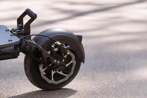 Rear wing with electric scooter wheel on asphalt background in sunny weather photo