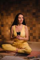 A girl in yellow clothes sitting on the floor holding pencils for drawing photo