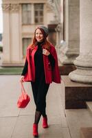 A beautiful stylish woman dressed in an elegant red coat with a stylish red handbag in the autumn city photo