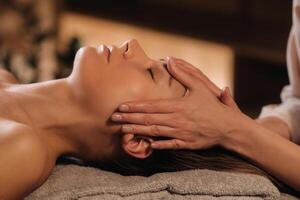 A cosmetologist girl does a facial and neck massage to a girl in the office for skin elasticity photo