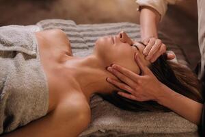 A cosmetologist girl does a facial and neck massage to a girl in the office for skin elasticity photo