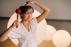 Portrait of a female yoga teacher playing a Tibetan bowl lying on her head in the gym during a yoga retreat photo