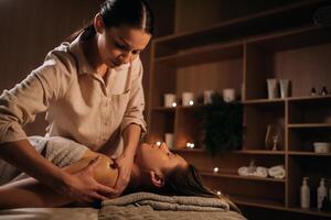 un masajista da un cuerpo masaje a un mujer en un spa centro. un profesional masajista masajes el hombro de un niña acostado en un spa centrar foto