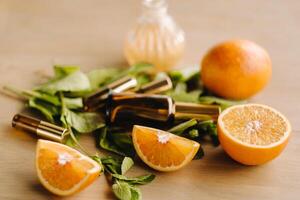 Essential oil in bottles with the aroma of orange and mint lying on a wooden surface photo