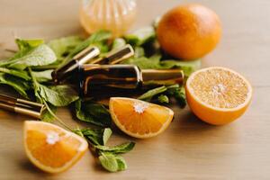 Essential oil in bottles with the aroma of orange and mint lying on a wooden surface photo