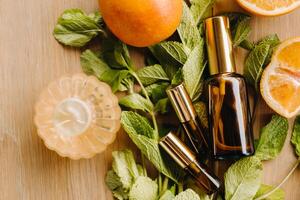 Essential oil in bottles with the aroma of orange and mint lying on a wooden surface photo