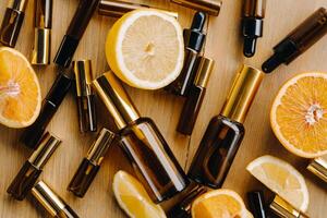 Essential oil in bottles and lemons, oranges lying on a wooden surface photo